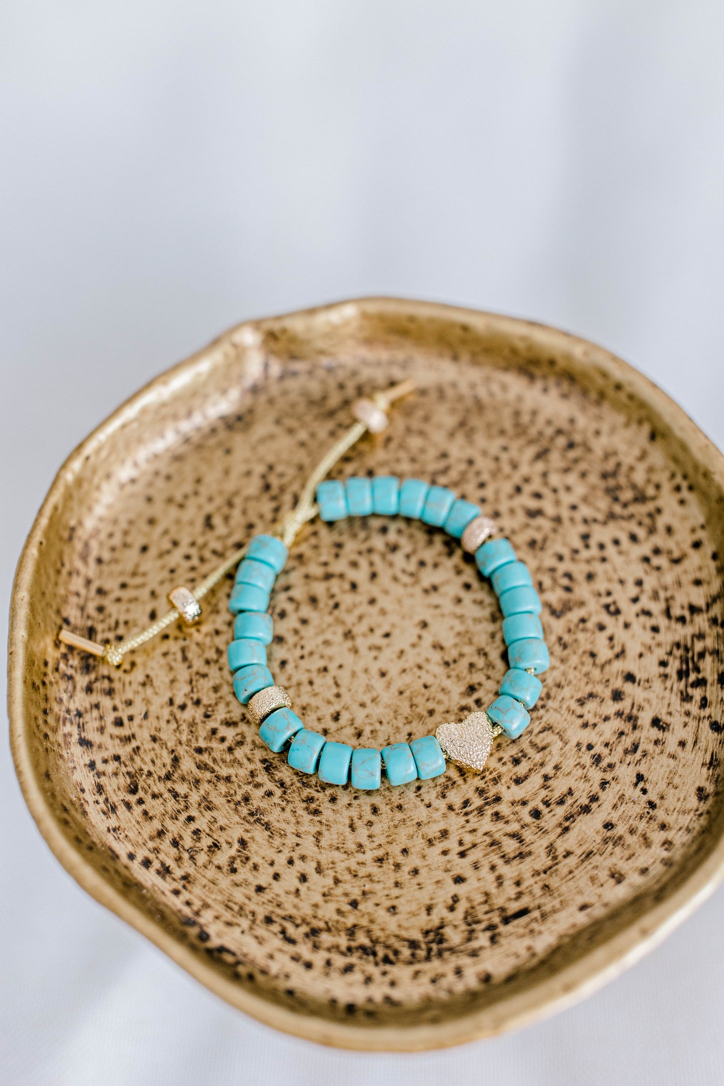 The perfect addition to your jewelry collection! This beautiful blue bracelet is made with forte gemstones and 18k gold filled stardust spacer beads that are strung on lurex cord with an adjustable sliding knot including a beautiful gold heart bead as a finishing touch. The blue forte beads have a gorgeous turquoise look to them for that lovely pop of blue. This bracelet can be made with or without the heart bead.