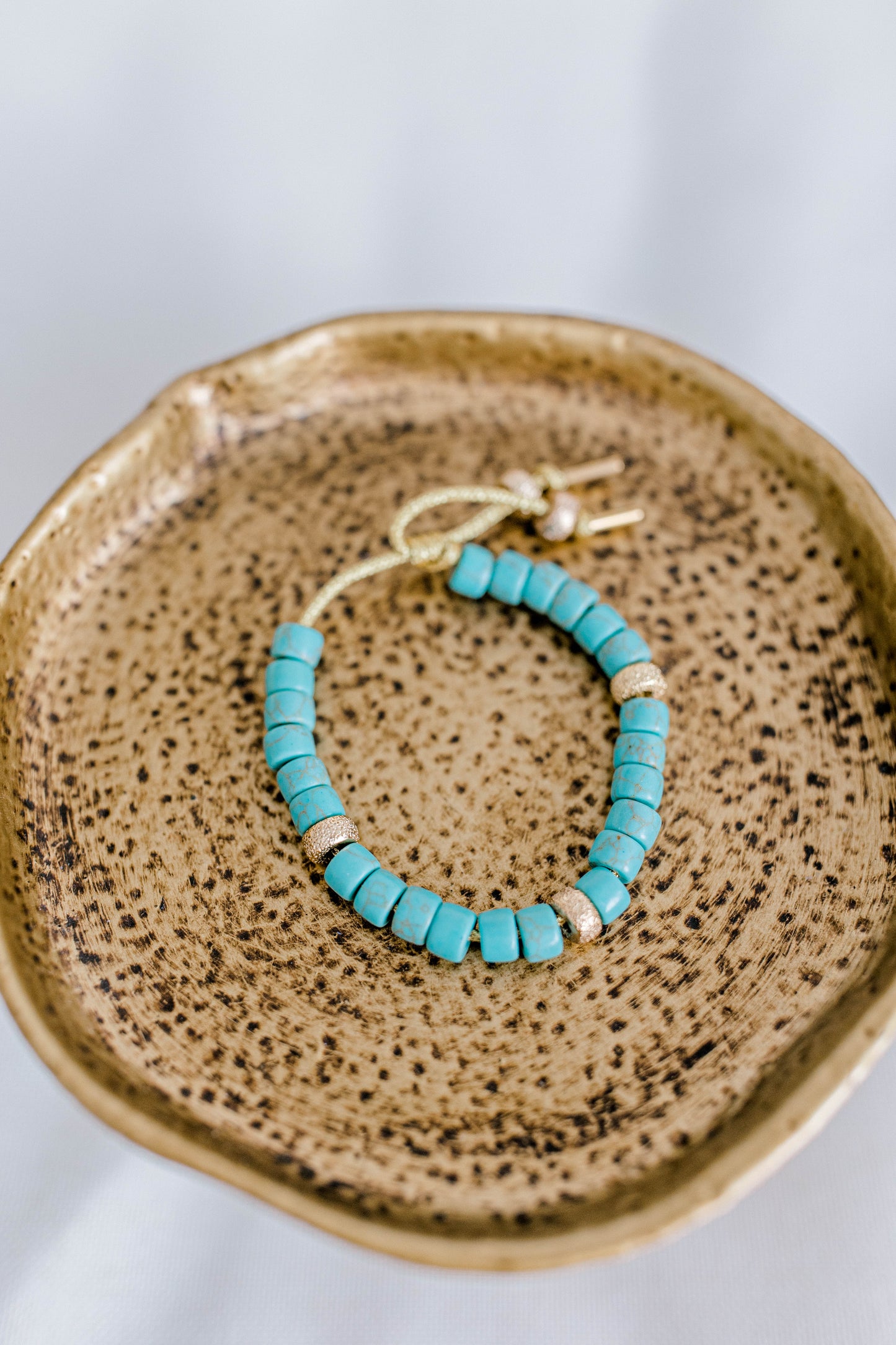 The perfect addition to your jewelry collection! This beautiful blue bracelet is made with forte gemstones and 18k gold filled stardust spacer beads that are strung on lurex cord with an adjustable sliding knot including a beautiful gold heart bead as a finishing touch. The blue forte beads have a gorgeous turquoise look to them for that lovely pop of color. This bracelet can be made with or without the heart bead.