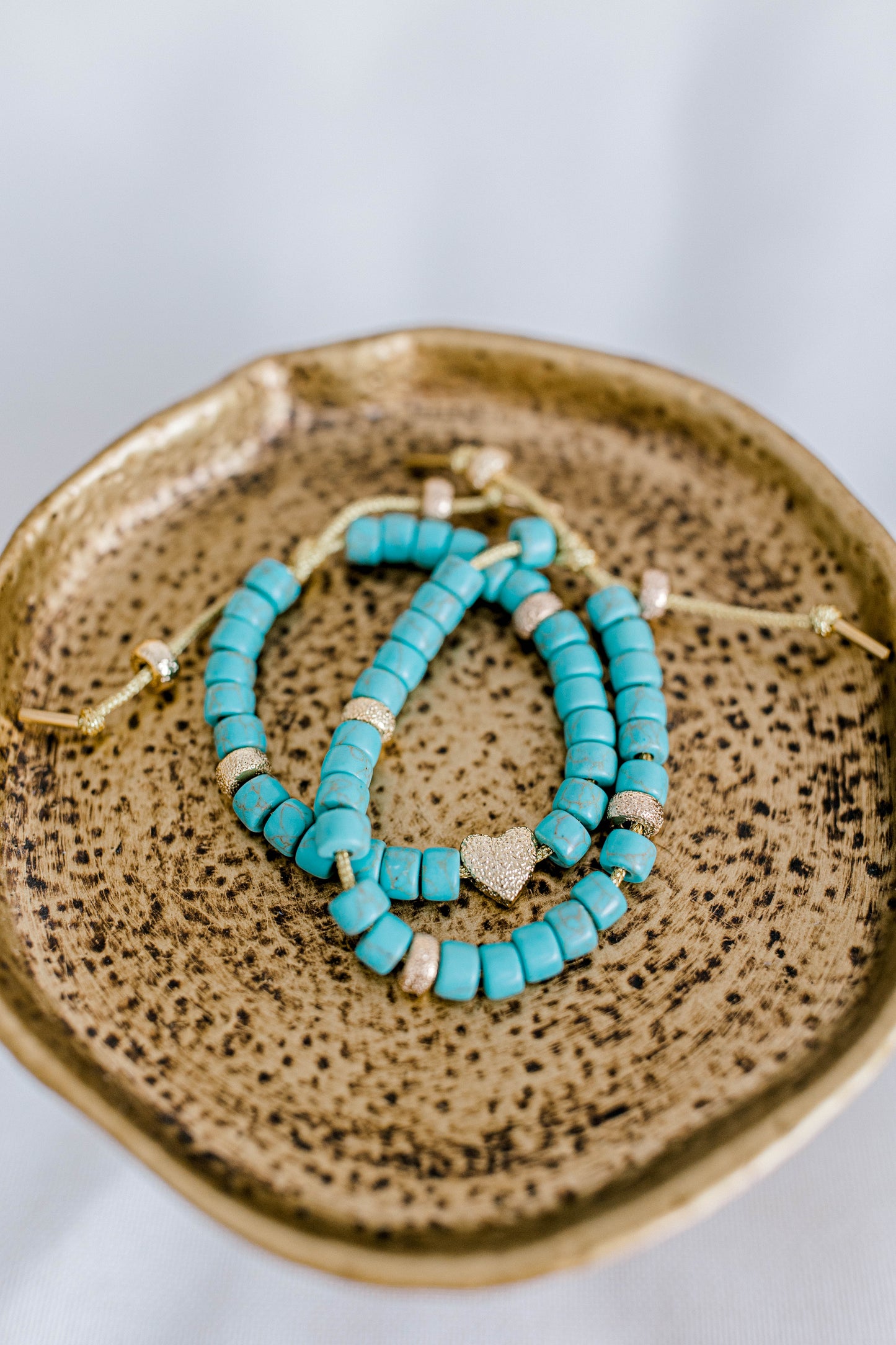 The perfect addition to your jewelry collection! This beautiful blue bracelet is made with forte gemstones and 18k gold filled stardust spacer beads that are strung on lurex cord with an adjustable sliding knot including a beautiful gold heart bead as a finishing touch. The blue forte beads have a gorgeous turquoise look to them for that lovely pop of color. This bracelet can be made with or without the heart bead.