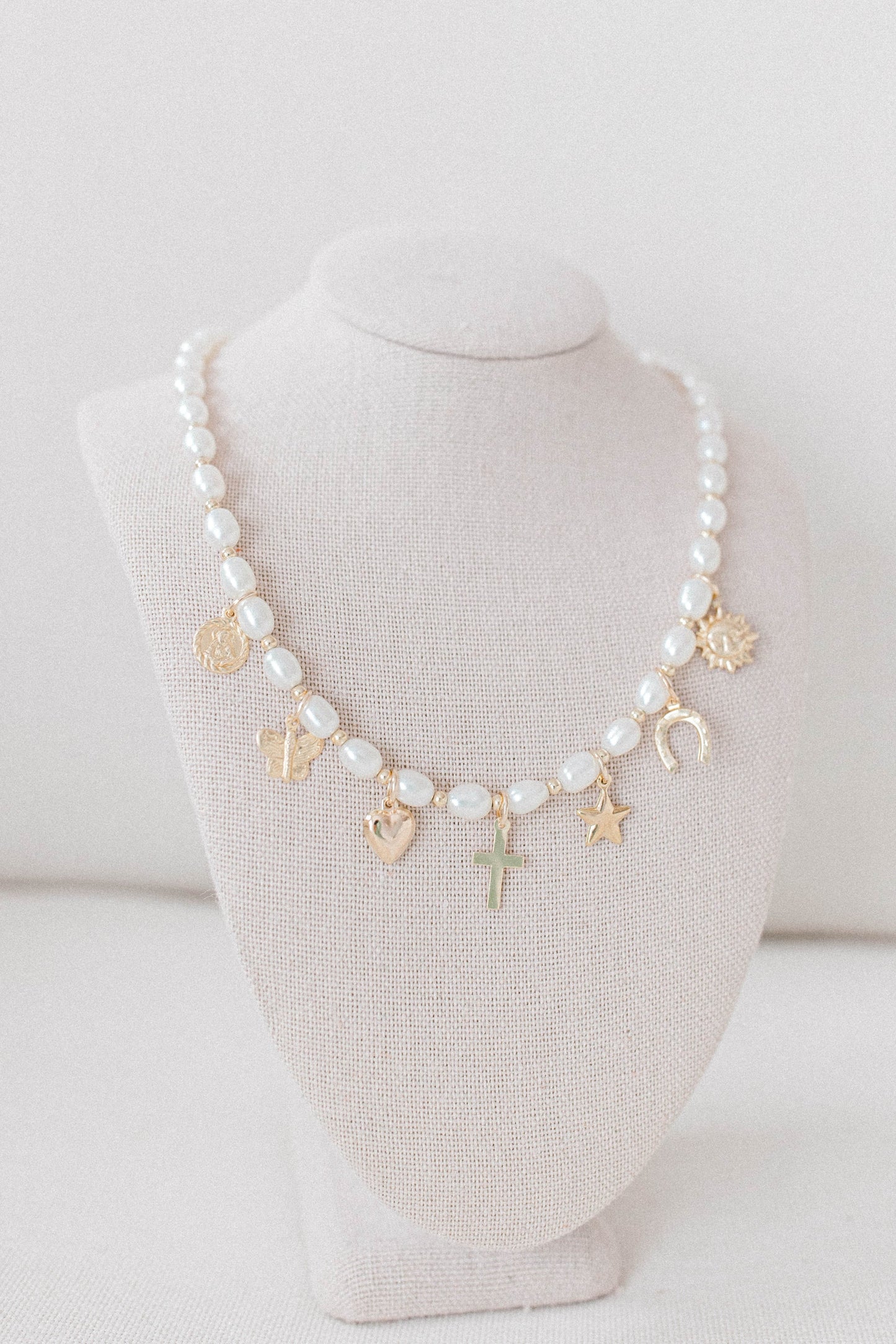 Custom charm necklace made with pearl beads, 14k gold filled spacer beads, and a collection of charms representing the He Left the 99 collection.