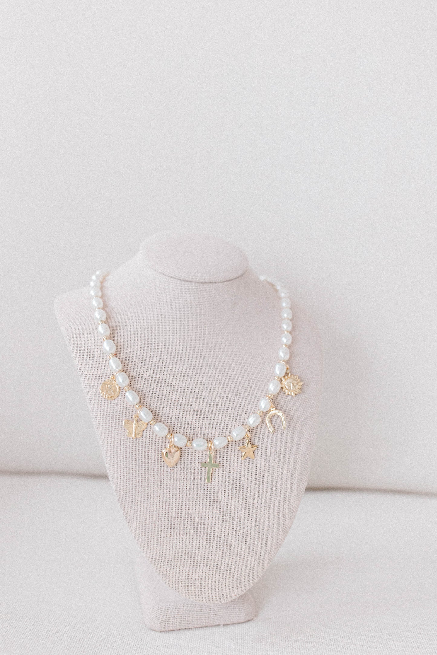 Custom charm necklace made with pearl beads, 14k gold filled spacer beads, and a collection of charms representing the He Left the 99 collection.