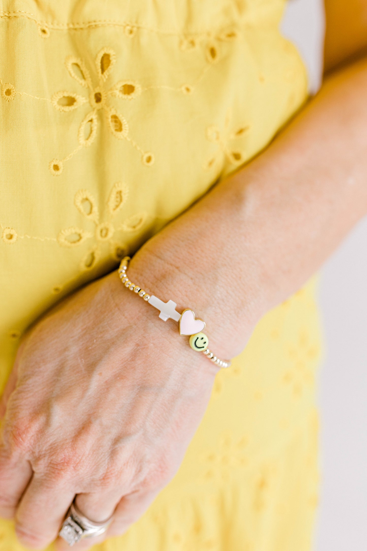 John 16:27 says, "for the Father himself loves you, because you have loved me and have believed that I came from God." This beautiful bracelet includes the Mother of Pearl cross, a pink enamel heart, and a yellow smiley face with 3mm gold beads.