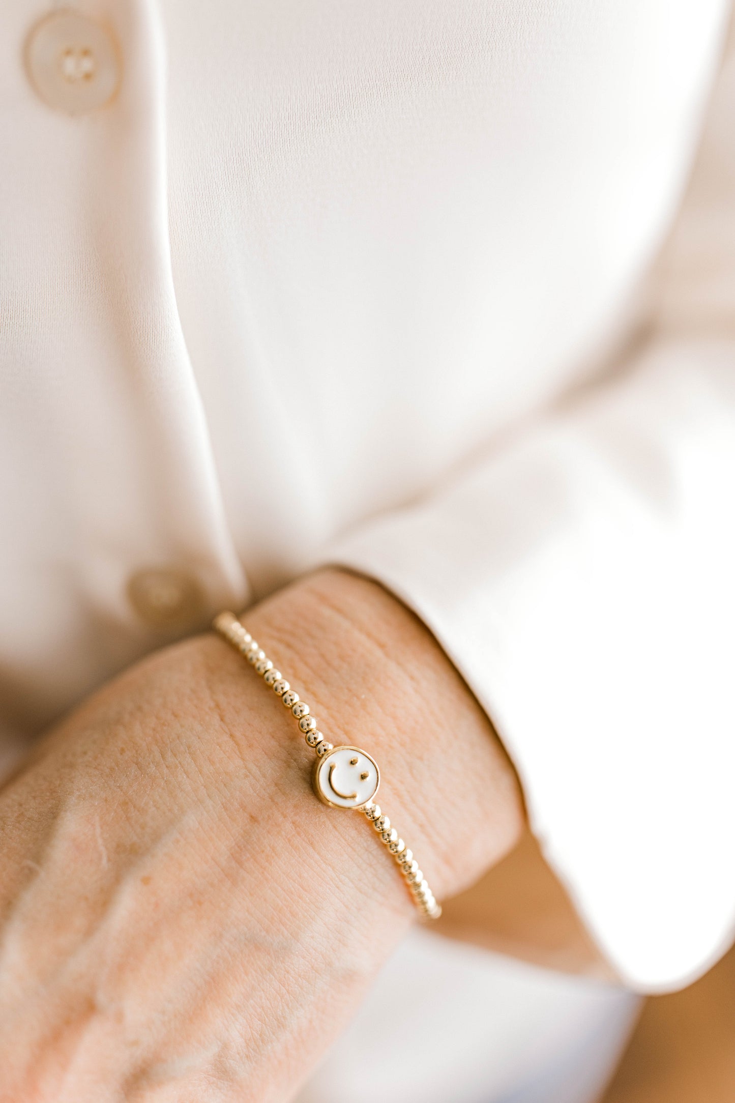 A super fun, yet simple, bracelet that's the perfect addition to any outfit! 3mm 14K gold filled with a white enamel smiley face spacer bead.