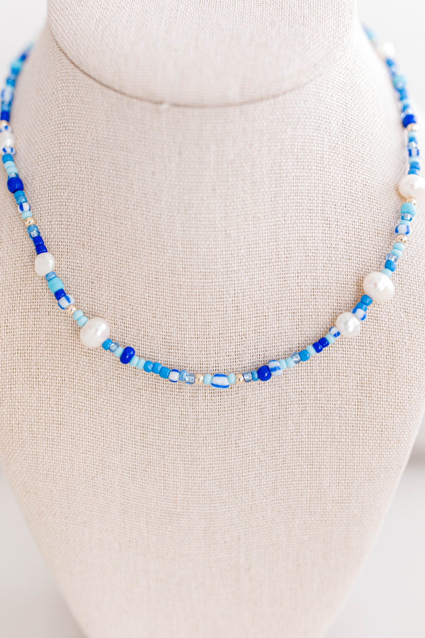 The perfect summer necklace is here and ready for the party! This beautiful necklace is made using multi color shades of blue seed beads, gold filled beads, and freshwater pearls creating a playful pattern for this necklace. This necklace is 15 inches with a 2 inch extender with a gold filled clasp and jump rings.